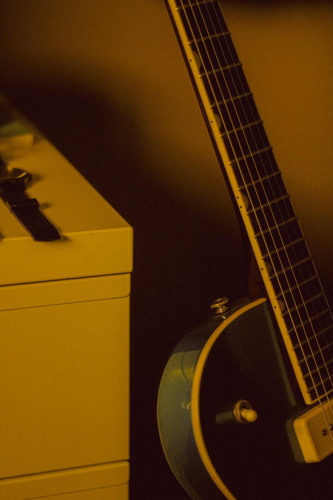 guitar next to cabinet in nostalgic yellow light